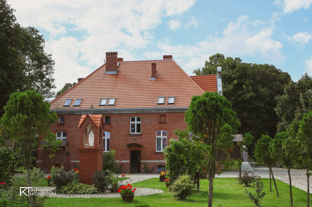 Współczesny widok Dworku na terenie Ośrodka Rehabilitacyjno-Wypoczynkowego w Sobieszewie, otoczonego zielenią.